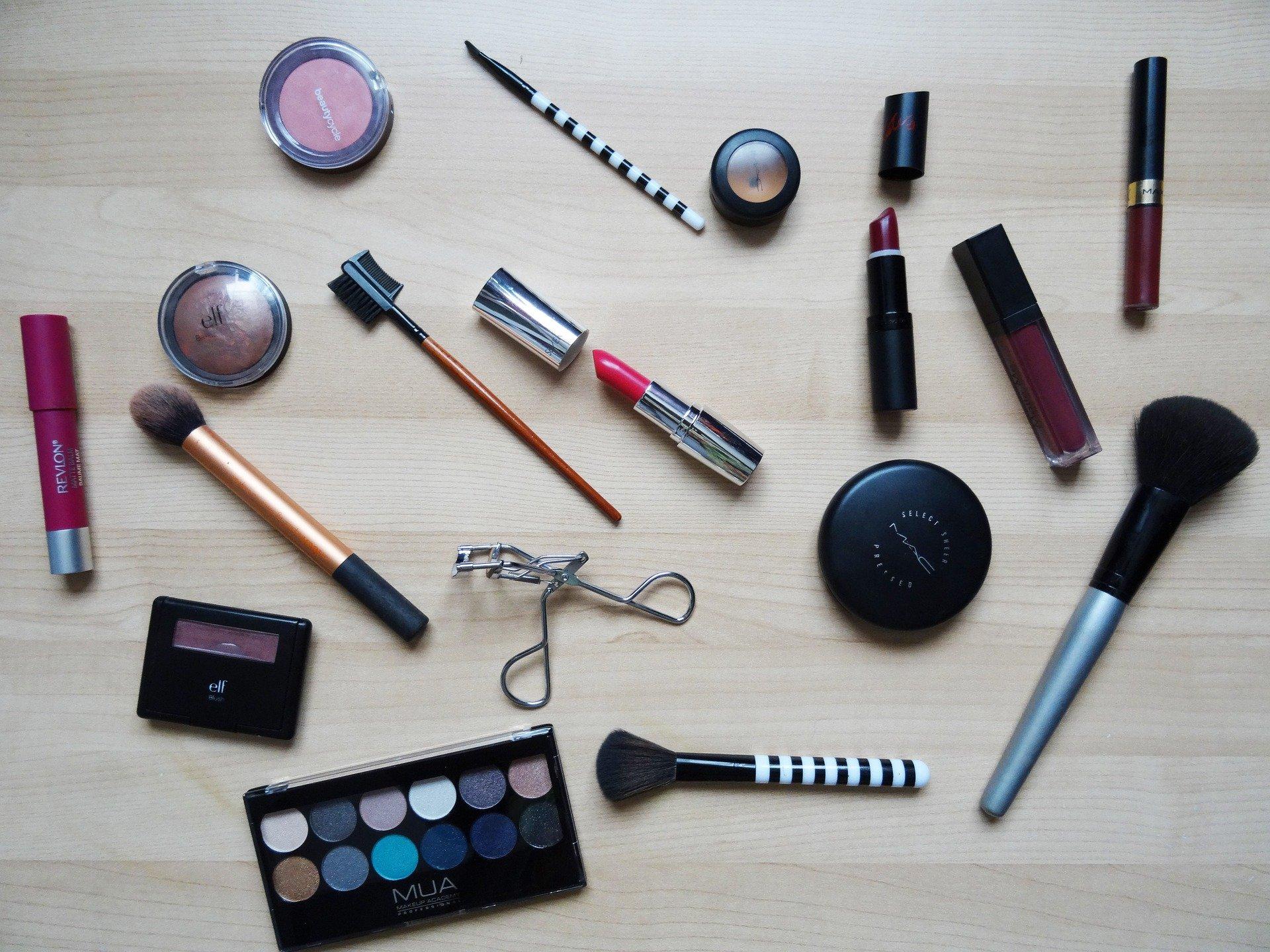 Photo de différents produits de maquillage : rouge à lèvres, fards à paupières, pinceaux