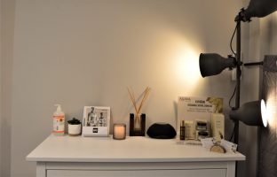 Photo d'un meuble avec différents produits et une bougie, une lampe sur le côté