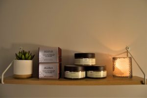 Photos de produits Ahava sur une étagère avec une bougie et une plante grasse
